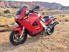 a red motorcycle is parked in the desert