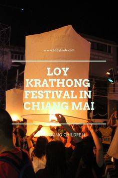 people are standing in front of a large white sign that says loy kratong festival in chang mai