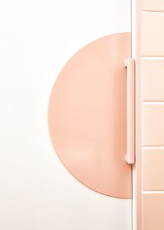 a bathroom with pink tiles and a round shaped mirror on the wall next to it