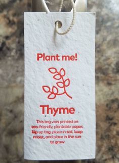 a plant me sign hanging from a rope