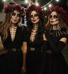 three women with skeleton makeup and flowers on their heads are standing in front of string lights