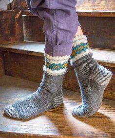 a person standing on some steps with their feet up and wearing socks that are knitted in different colors