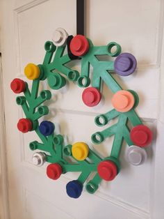 a wreath made out of legos is hanging on the front door with colorful buttons