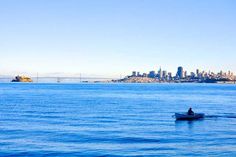 a person in a small boat on the water with a city skyline in the background