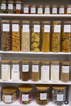 the shelves are filled with different types of cereals and other food items in glass containers