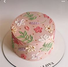 a pink cake decorated with flowers and leaves