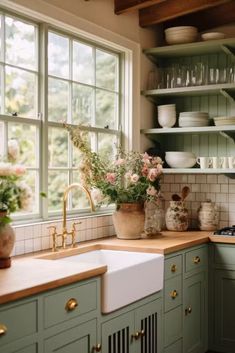 a kitchen filled with lots of green cupboards and white counter tops next to a window