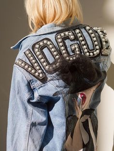 the back of a woman's jean jacket with beaded letters on it