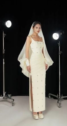 a woman in a white dress and veil posing for the camera with lights behind her