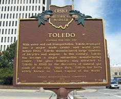 a sign in front of a tall building that says toledo with water and rail transportation, tokyo - developed