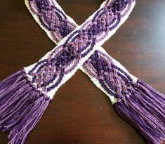 a purple and white scarf sitting on top of a wooden table