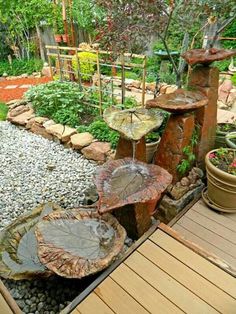 an outdoor garden with rocks, plants and water features