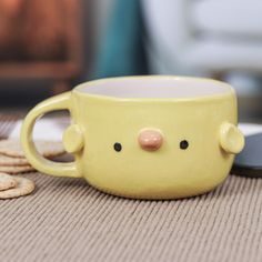 a yellow cup with a face on it sitting next to crackers