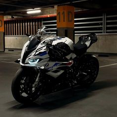 a white and black motorcycle is parked in a parking garage with no one around it