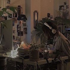 a woman sitting at a desk with headphones on and plants in front of her