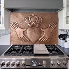 a stove top oven sitting inside of a kitchen next to a wall mounted plaque with two hands and a crown on it