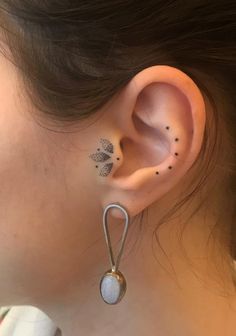 a woman's left ear has a dandelion tattoo on her right side