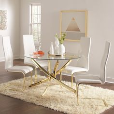 a glass table with white chairs and a rug in front of it on the floor