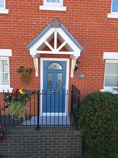 a red brick building with a blue front door and black iron fence on the sidewalk