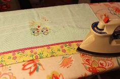 an iron is sitting on top of a table with a flowered cloth and fabric