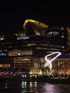 an image of a city at night with lights on the water and buildings in the background