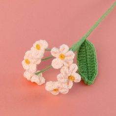 crocheted flowers on a pink surface with one flower attached to the end of it