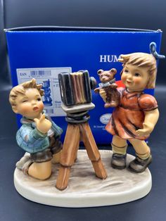 two figurines are standing next to each other near a blue box with the word humm on it