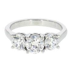 This three stone engagement ring features a 0.70 carat round brilliant cut center, E color, VVS2 clarity and is flanked by a 0.50 carat round diamond on each side, both in the same color and clarity as the center diamond. The Diamonds are set on a classic high polish Platinum shank for a traditional look that never goes out of style. Finger size: 6 Three Stone Platinum Diamond Ring, Classic Platinum Three-stone Ring, Classic Platinum Three Stone Rings, Timeless Platinum Three-stone Ring, Platinum Three Stone Ring With Round Band, Timeless Three Stone Diamond Ring In White Gold, Timeless White Gold Three Stone Diamond Ring, Timeless Three Stone Platinum Wedding Ring, Classic Three-stone Cubic Zirconia Diamond Ring