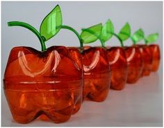 four red glass apples with green leaves in them on a white surface, lined up against each other