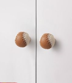 two baseballs are hanging on the door knobs in front of a white cabinet