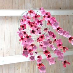 pink paper flowers are hanging from a wire