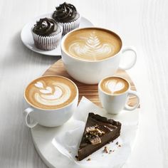 two cups of coffee and one slice of cake on a plate