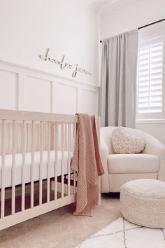 a baby's room with a white crib, chair and blanket on the floor