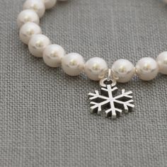 "This dainty pearl and Sterling Silver snowflake bracelet makes the perfect gift for your bridesmaidsand coordinates well with my snowflake bracelets and necklaces (https://www.etsy.com/shop/SprigJewelry?ref=hdr_shop_menu&search_query=snowflake). The snowflake measures approximately 1/2\" across, with a 6mm pearl. Please select the length and pearl color you would like from the drop down menus at checkout. The last photo shows the pearl colors that Swarovski has available, double clicking on White Snowflake Jewelry For Formal Occasions, White Snowflake Jewelry Gift, Christmas White Gold Snowflake Jewelry, Beaded Snowflake Bracelet, Wedding Pearl Jewelry, Snowflake Bracelet, Snowflake Jewelry, Pearl Jewelry Wedding, Silver Snowflakes