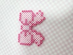 a pink and white cross stitched brooch on a checkered tablecloth background