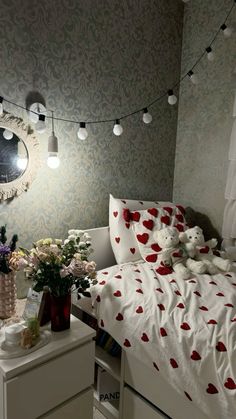 a bedroom decorated in white and red with teddy bears on the bed next to it