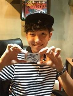 a young man holding up a cell phone in front of his face while wearing a black and white striped shirt