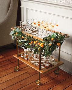 there are many glasses on the table with oranges and greenery in them,