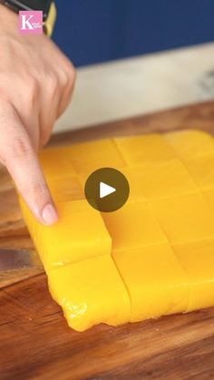 a person cutting cheese on top of a wooden table