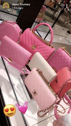 four pink and white purses sitting on top of a glass table next to each other