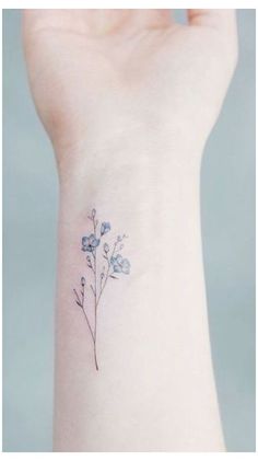 a small blue flower tattoo on the wrist