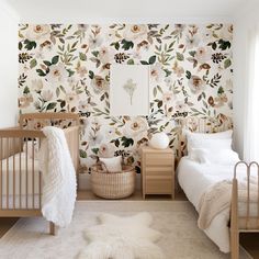 a baby's room with floral wallpaper and two cribs next to each other