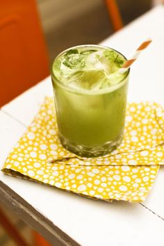 a green drink sitting on top of a yellow napkin