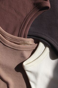 two sweaters are folded up on top of each other, one is brown and the other is white