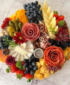 a platter filled with lots of different types of cheeses and fruit on top of a table