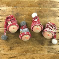 three snowmen wearing hats and scarves on top of a wooden table