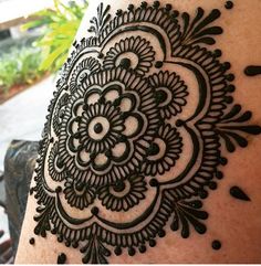 a woman's arm with black henna tattoos on the back of her shoulder