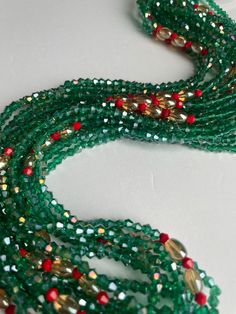 Elastic waist beads, made by skilled artisans in the Ivory Coast. This striking piece features deep green crystal glass seed beads complemented by vibrant red crystal glass seed bead accents, blending nature's tranquility with bold energy. Cultural Significance: In the Ivory Coast, waist beads hold deep cultural meaning as symbols of femininity, sensuality, and personal growth. Traditionally worn to celebrate significant life events, these beads connect wearers to their heritage and empower their personal journeys. Design and Craftsmanship: Materials: High-quality crystal glass seed beads Colors: Deep Green: Represents growth, harmony, and renewal Red Accents: Symbolizes passion, vitality, and strength Fit: Elastic band ensures a comfortable and flexible fit for all body types Wear with Pu Gemstone Waist Beads As Gift, Gift Gemstone Waist Beads, Green Multi-strand Beads For Gifts, Traditional Green Beaded Bracelets With Spacer Beads, Bohemian Green Waist Beads With Colorful Beads, Green Tiny Round Beads Waist Beads, Festive Green Beaded Bracelets With Colorful Beads, Festive Green Beaded Bracelets, Green Gemstone Party Beads