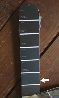 a wooden table topped with lots of different shades of gray and white paint swatches