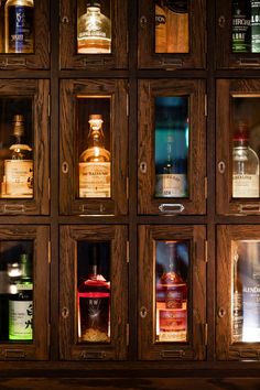 many bottles of different types and sizes are on display in a wooden case with glass doors